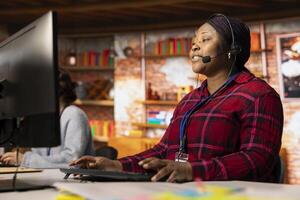 Jolly call center professional typing on PC keyboard, assisting customers through digital communication channels. Friendly customer support representative in live chat with client photo
