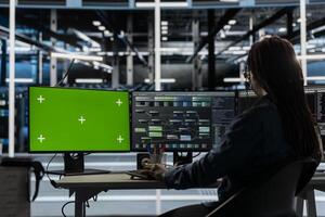 Server room technician using artificial intelligence tech on green screen PC to reduce downtime. Admin using chroma key computer to design and implement AI driven solutions for data center equipment photo
