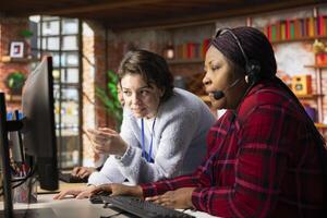 Cheerful call center onboarding specialist training worker on how to use computer software. Happy supervisor in customer support department office showing employee how to use company application photo