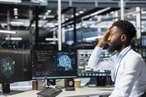 Data center admin troubled by errors while using machine learning algorithms to analyze datasets. Server farm worker doing face palm after glitch found while using AI to recognize data patterns photo
