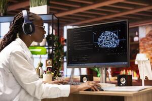 Engineer using computer at home for artificial intelligence computing through self learning algorithms, wearing headphones. Remote employee works with AI neural networks on desktop PC, listening music photo