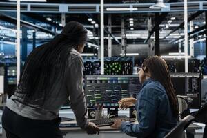Server room manager overseeing work done by engineer using artificial intelligence to reduce downtime. Team leader supervising employee implementing AI driven solutions for data center equipment photo
