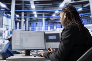Engineer coding at workstation in solar panel manufacturing plant, developing programs to automate equipment processes. Photovoltaics factory expert writing scripts to optimize robotic operations photo