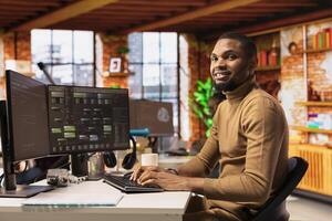 Portrait of cheerful IT technician using PC in innovative startup office and programming languages to build applications. Joyous software development agency IT expert optimizing code on computer photo