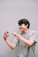 Cheerful Asian man engaging with mobile phone app with joyful expression photo