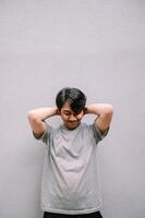 Relaxed Asian Man with Hands Behind Head Posing on Gray Background photo