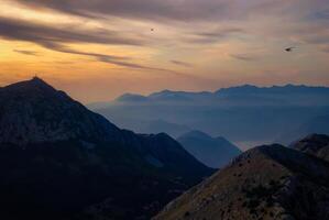 Scenic sunset over a dramatic mountain range with layered ridges fading into the distanc photo