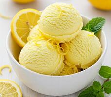 Close-up of a white bowl filled with three scoops of lemon creamy ice cream, garnished with a fresh lemon fruit slice and mint leaves. photo