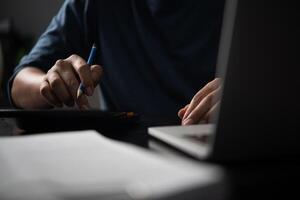 A person using a calculator and a laptop photo