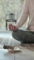 Serene woman practicing yoga and meditation, using white sage smudge stick for spiritual cleansing, creating peaceful atmosphere within comfortable home interior with soft natural light video
