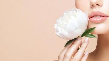 Close-up of a young Caucasian flower with light pink lips holding a white peony woman against a soft peach background. The focus is on her lips and the flower. photo