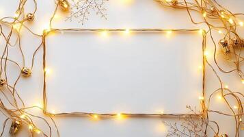 Christmas fairy lights forming a rectangular frame on golden white background with a bells and dried flowers, creating a festive holiday mood photo