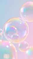 Colorful soap bubbles in various sizes float against a soft pink background. The bubbles display shades of blue, pink, and clear reflections. photo