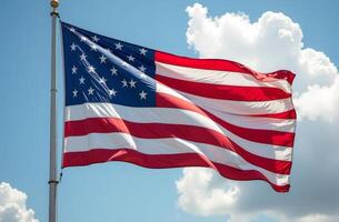 American flag waving under a clear blue sky with fluffy clouds in the background during a sunny day photo