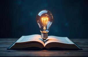 An open book with a glowing light bulb positioned above it on a dark wooden surface photo