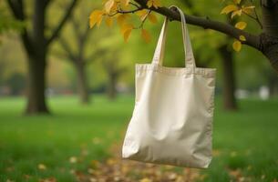 A natural setting featuring a hanging tote bag on a tree branch in a lush green park during autumn photo