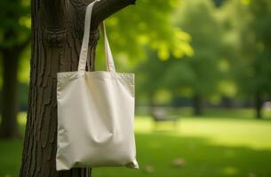 A simple tote bag hanging on a tree branch in a sunlit park during a bright afternoon photo