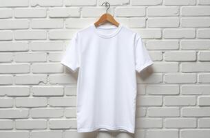 Clean white t-shirt displayed on a wooden hanger against a textured white brick wall in a well-lit space photo