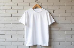 Minimalist white t-shirt displayed on a wooden hanger against a textured brick wall in a well-lit setting photo