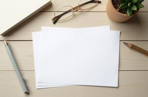 A workspace setup with blank pages, glasses, and a potted plant on a wooden table, ideal for writing or drawing at midday photo