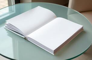 Blank notebook resting on a glass table beside a window in a bright, cozy room during the daytime photo