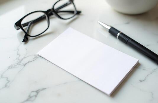 A blank notepad, pen, and glasses positioned on a marble surface, perfect for brainstorming or note-taking in a calm workspace environment photo