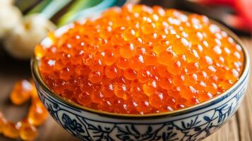 Fresh salmon roe garnished in a decorative bowl on a wooden table with culinary elements in the background photo