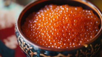 Vibrant orange salmon roe displayed in an intricately designed bowl during a festive gathering photo