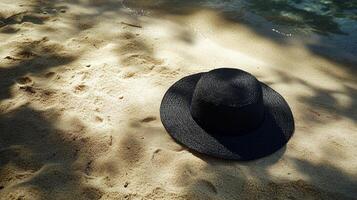 Relaxing beach scene featuring a black straw hat lying on sandy shore under dappled sunlight photo