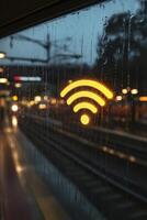 Rainy evening at the train station with WiFi symbol illuminated through a fogged window photo