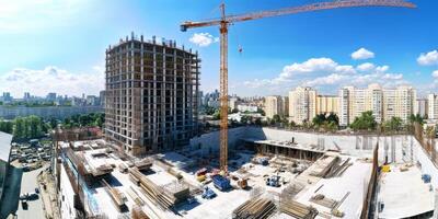 Construction of a high-rise building in an urban location during a sunny day with clear skies and a construction crane photo