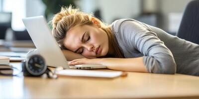 Young woman falling asleep while working at a laptop in a modern office environment during a busy workday photo
