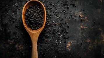 Freshly ground black pepper displayed in a wooden spoon on a rustic countertop photo