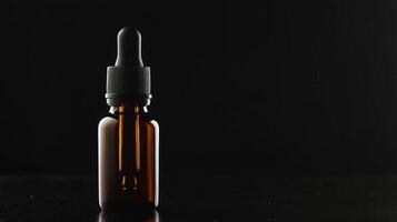 Glass bottle with dropper against dark background highlighting its robust amber color and minimalist design photo