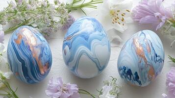 Decorative blue and white marbled Easter eggs arranged with fresh flowers on a light backdrop photo