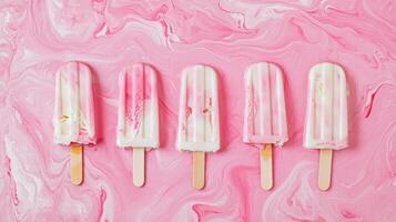 Colorful ice pops arranged on a pink swirled background evoking summer vibes and sweet treats for all ages photo
