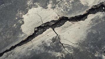 Cracked pavement showing signs of erosion and weathering in an urban area during daylight hours photo