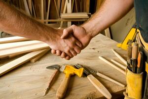 Two individuals shaking hands in a woodworking shop surrounded by tools and wooden planks during the daytime photo