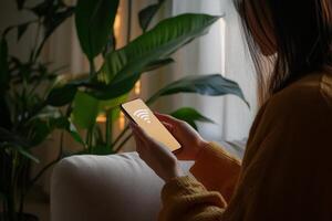 Woman browsing on smartphone with WiFi symbol in cozy living room surrounded by greenery photo
