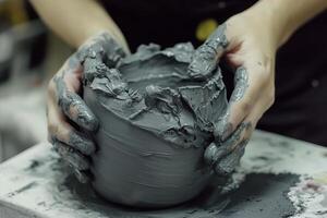 Hands shaping a gray clay pot at a pottery studio during an afternoon crafting session photo