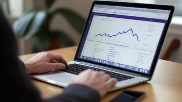 Person analyzing data trends on a laptop at a desk during daytime in an indoor setting photo