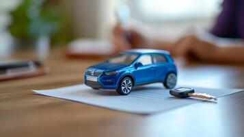 Miniature blue car and key placed on paperwork in an office setting during a daytime transaction photo