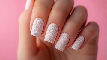 Elegant light textured nail art showcased against a soft pink backdrop photo