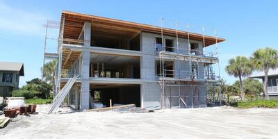 Modern building construction in sunny coastal location with scaffolding and palm trees surrounding site photo
