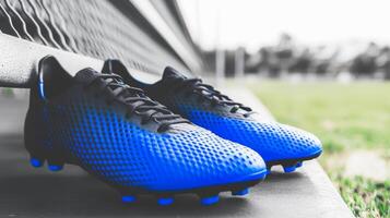 Stylish blue soccer cleats placed on a bench at a sports field during cloudy afternoon photo