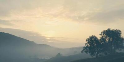Serene landscape with misty hills and soft sunrise glow over distant trees photo