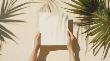 Hands holding a blank sheet of paper amidst tropical palm leaves in bright sunlight photo