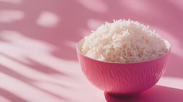 Textured pink bowl filled with fluffy white rice against a pastel background showcasing shadows and light play photo