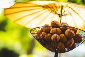Freshly harvested nuts displayed under a vibrant yellow umbrella in a sunny outdoor setting photo