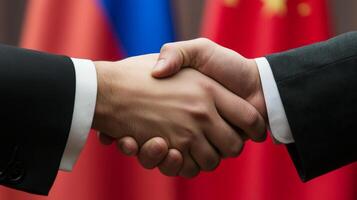 Handshake between representatives of Russia and China with national flags in the background during diplomatic meeting photo